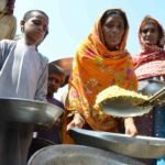 Flood-affected people queue for food distributed at Dera Allah Yar town of Jaffarabad district in Balochistan province on September 17, 2022. (Photo by Fida HUSSAIN / AFP)